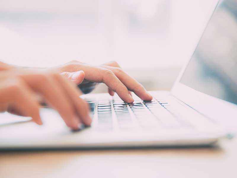 Hands typing on a laptop